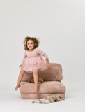 Child in a pink dress sitting on a Rylee Recliner chair with a white background