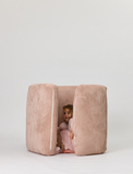 Child peeking out from a pink cushioned playpen on a white background