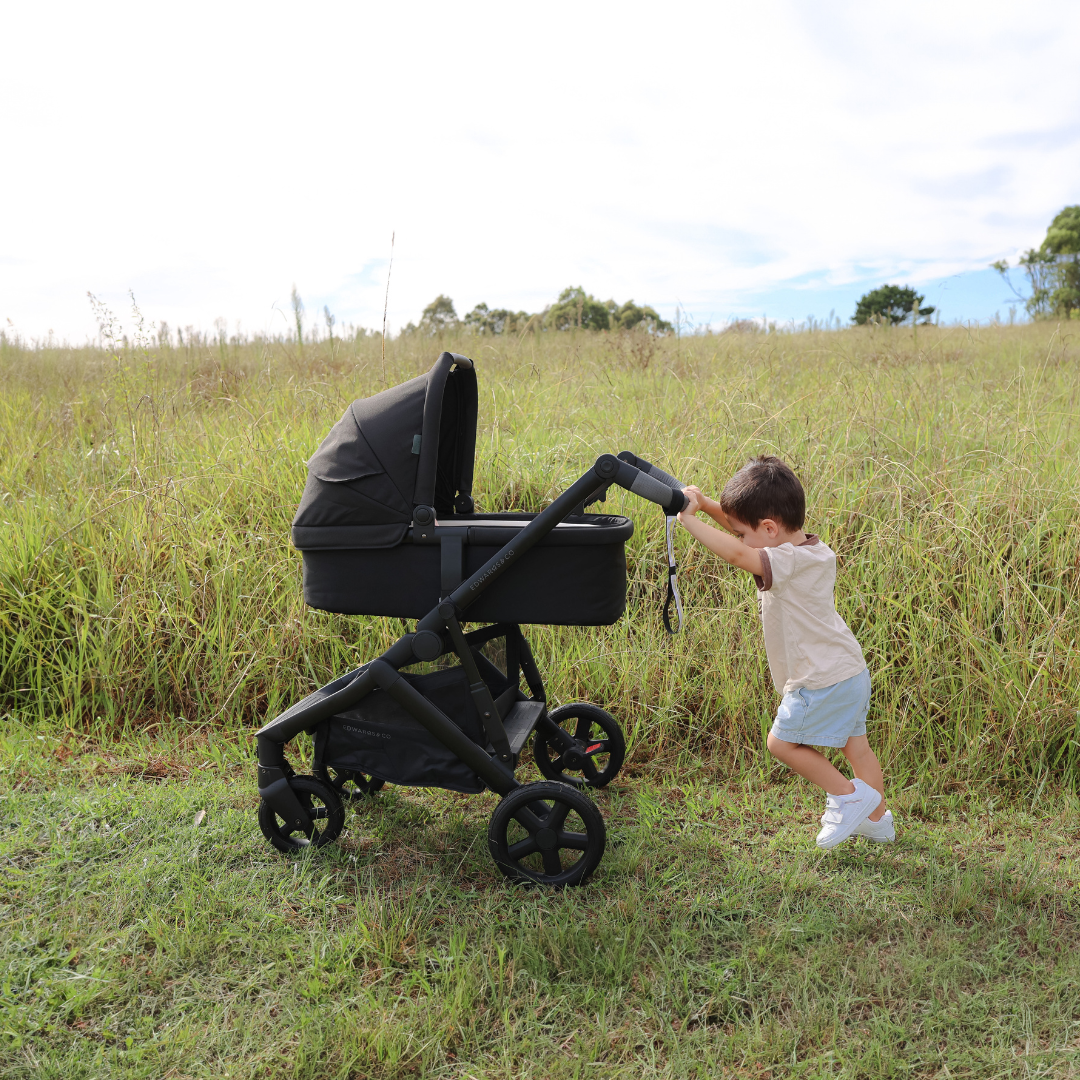 Kid holding and pushing Olive pram from Edwards & Co