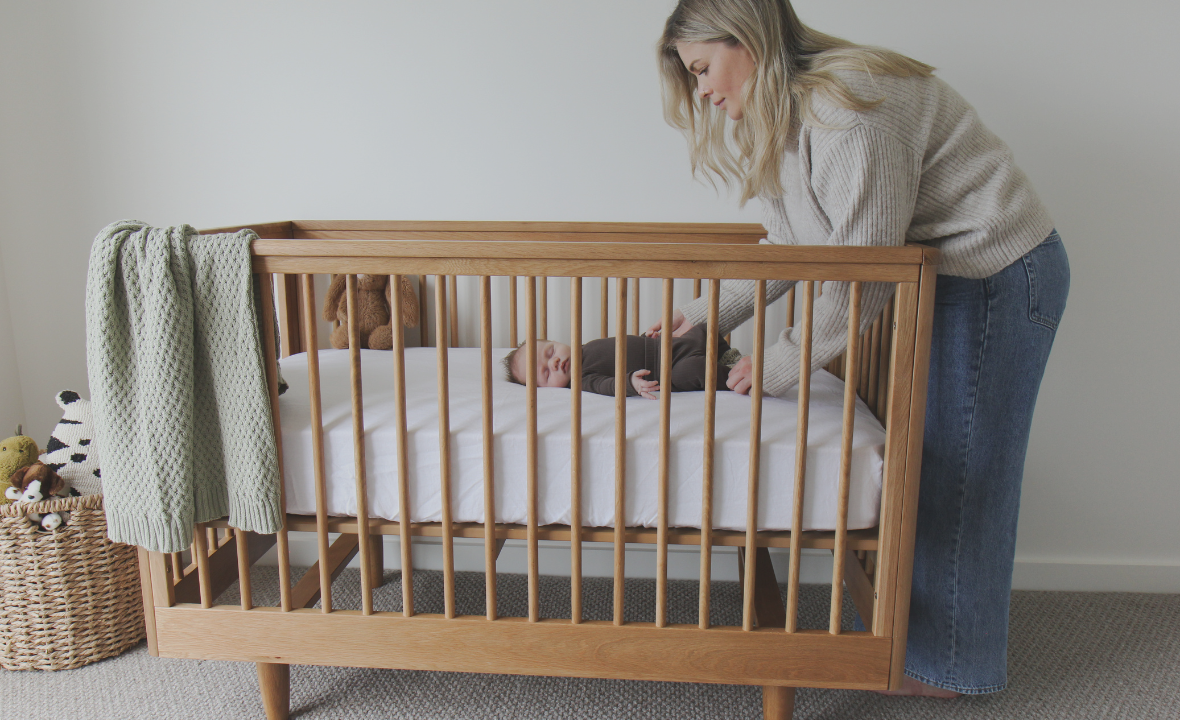 Mother putting the baby in the George Cot