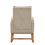Myla Nursery Chair shown from the back, featuring textured beige fabric upholstery and a light brown wooden frame with curved legs.