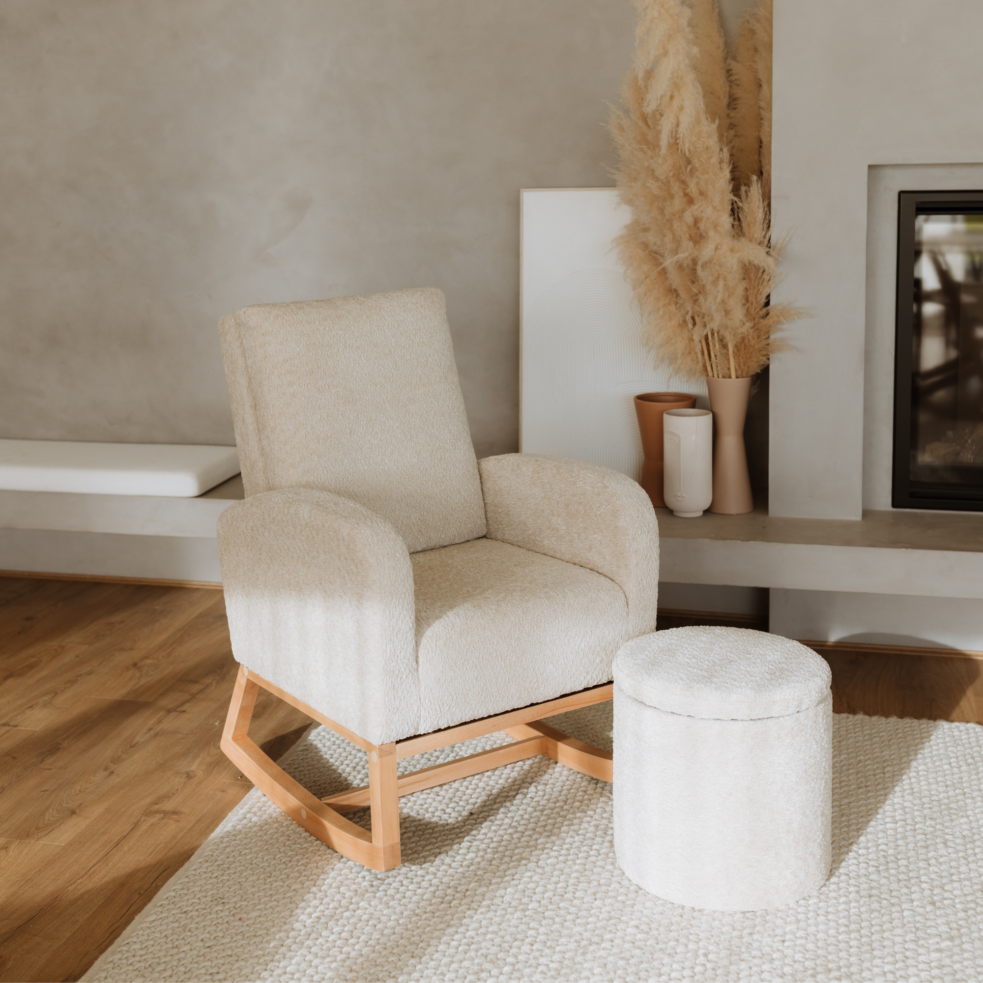 A cream-colored upholstered Myla & Mylo with a natural wood rocking base, shown in a styled living room setting next to a matching round ottoman.