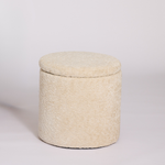 Mylo Ottoman covered in a textured cream bouclé fabric, set against a plain light gray studio background.