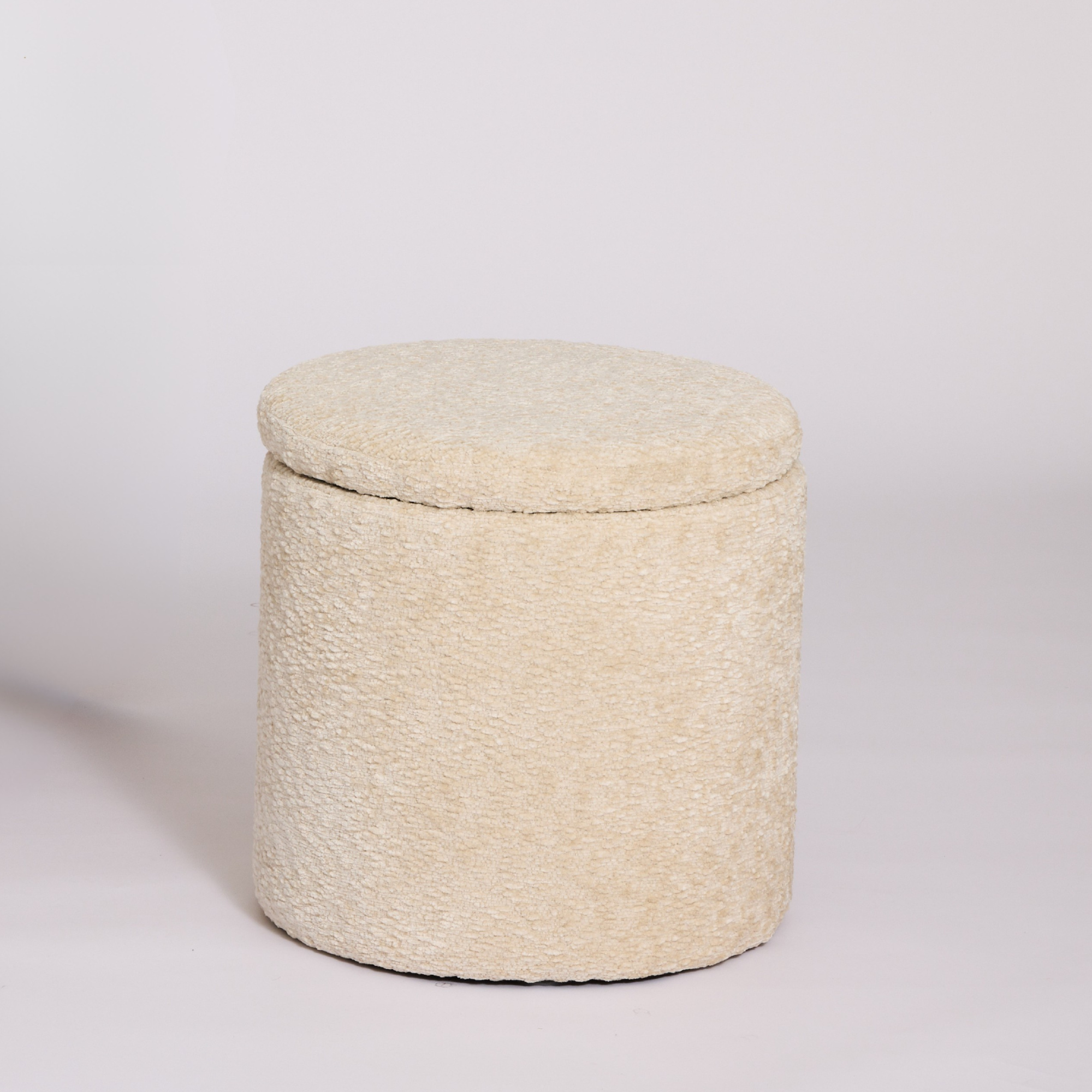 Mylo Ottoman covered in a textured cream bouclé fabric, set against a plain light gray studio background.
