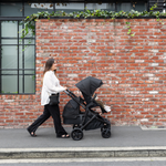 Mother walking on a street with Olive pram from Edwards & Co